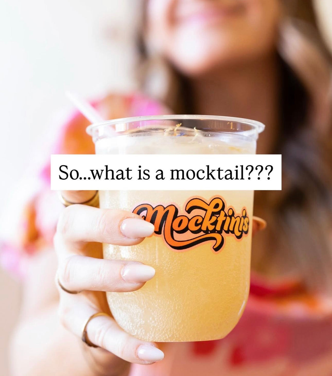 smiling woman holding a garnished mocktail