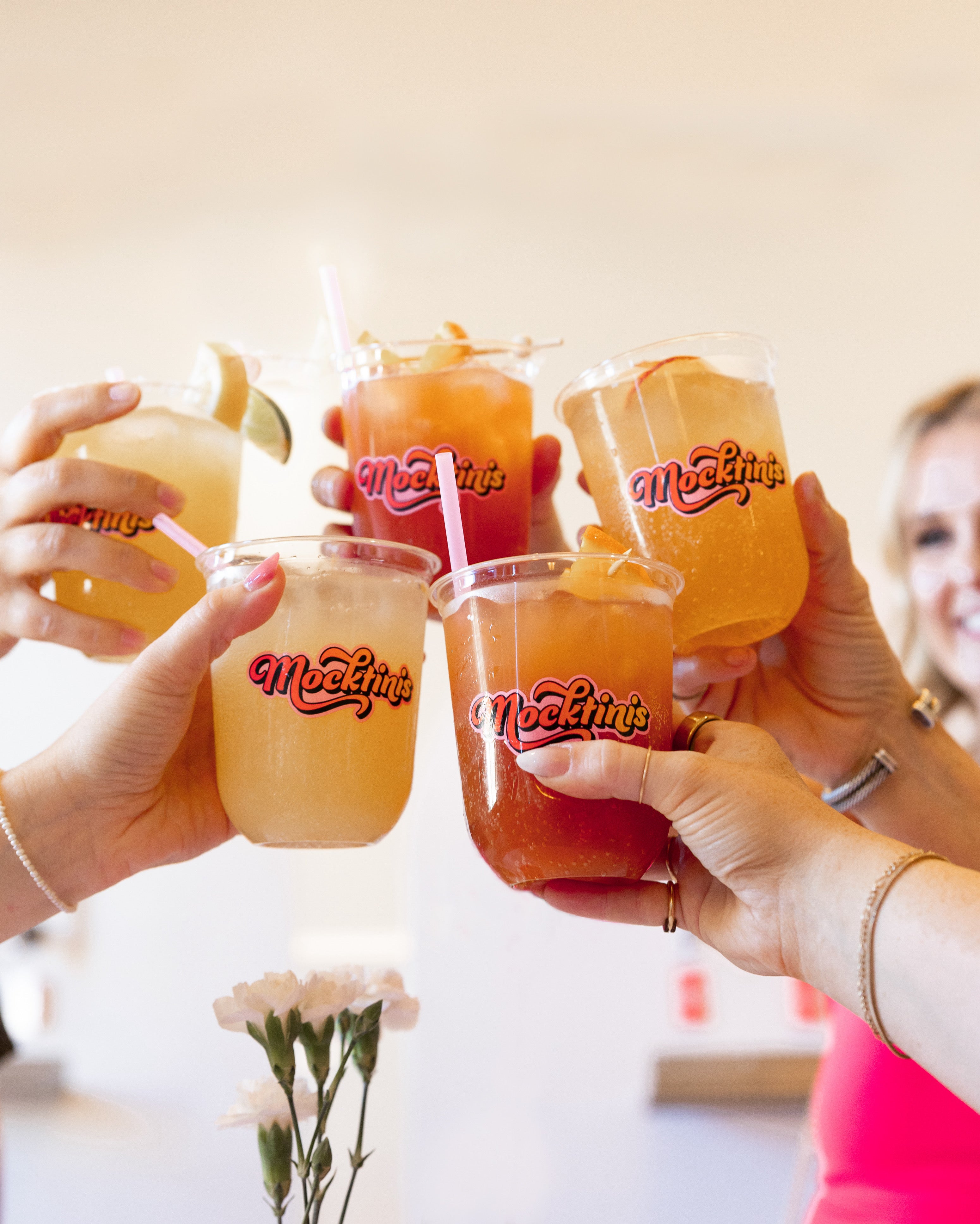 people holding up Mocktinis cups and cheersing