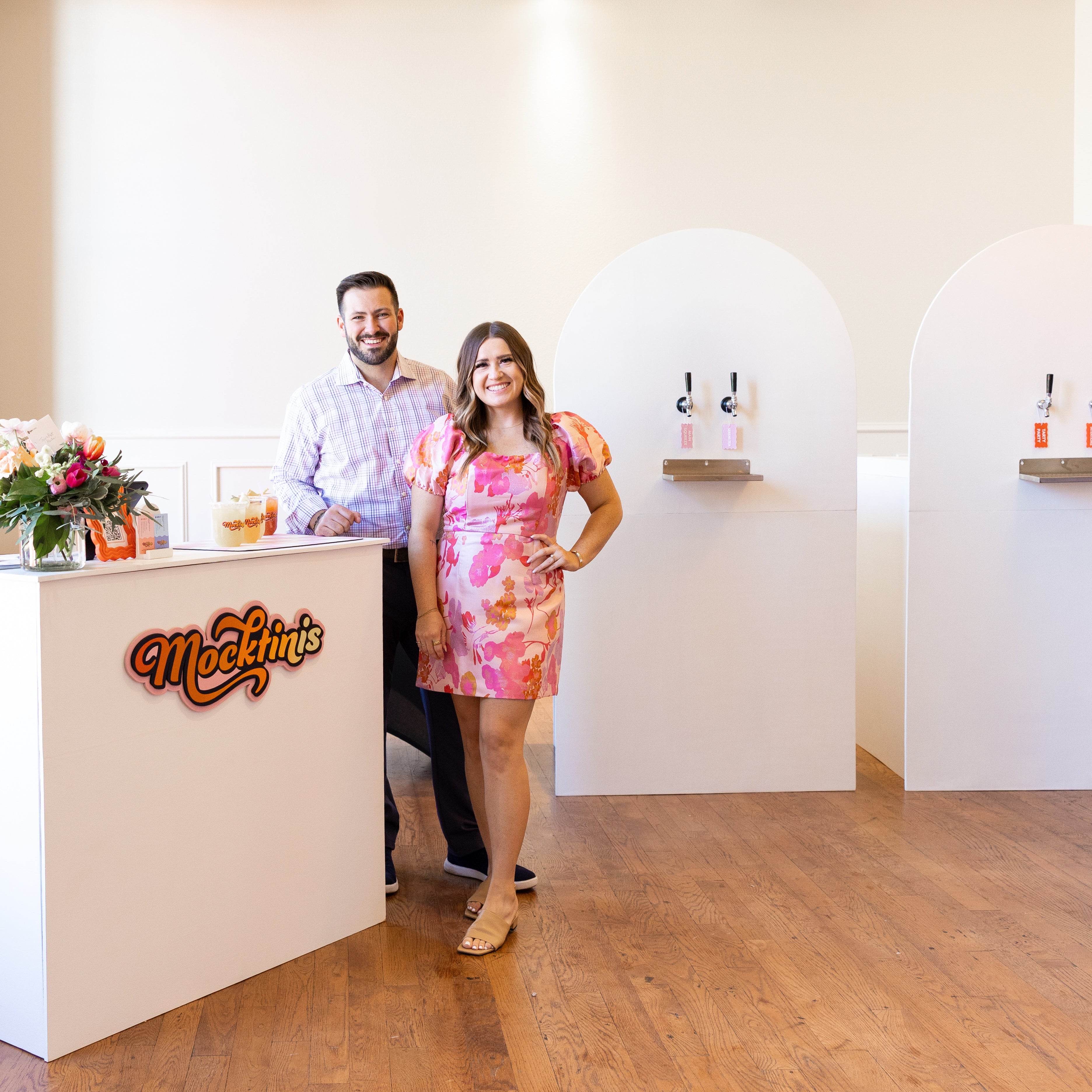 the owners of Mocktinis standing in front of their bar and custom tap walls