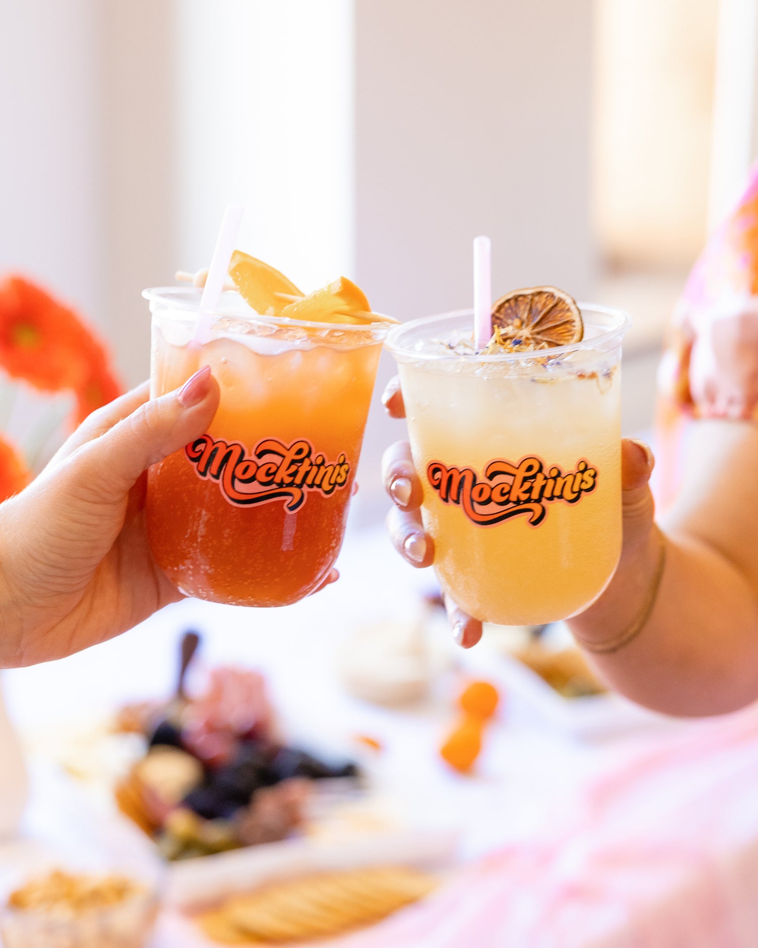 two hands holding garnished mocktails